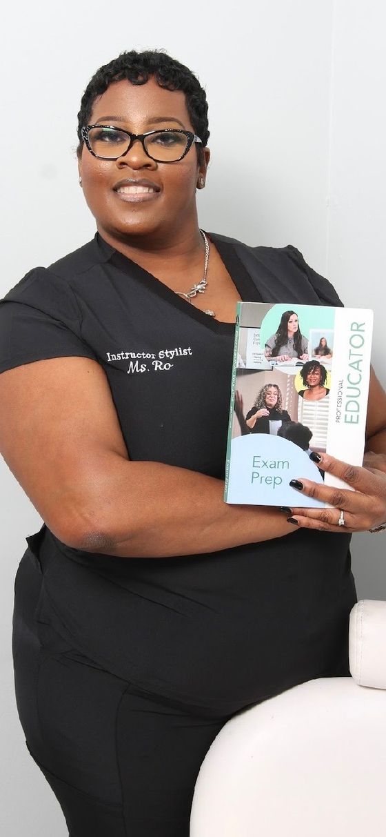 Ro in her Instructor Stylist tee, holding a professional educator exam-prep book